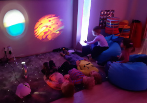 Dzieci leżą na podświetlanym dywanie.